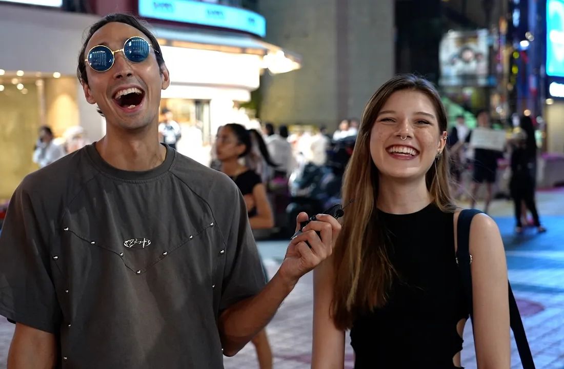 Sean laughing with an interviewee during a night street interview